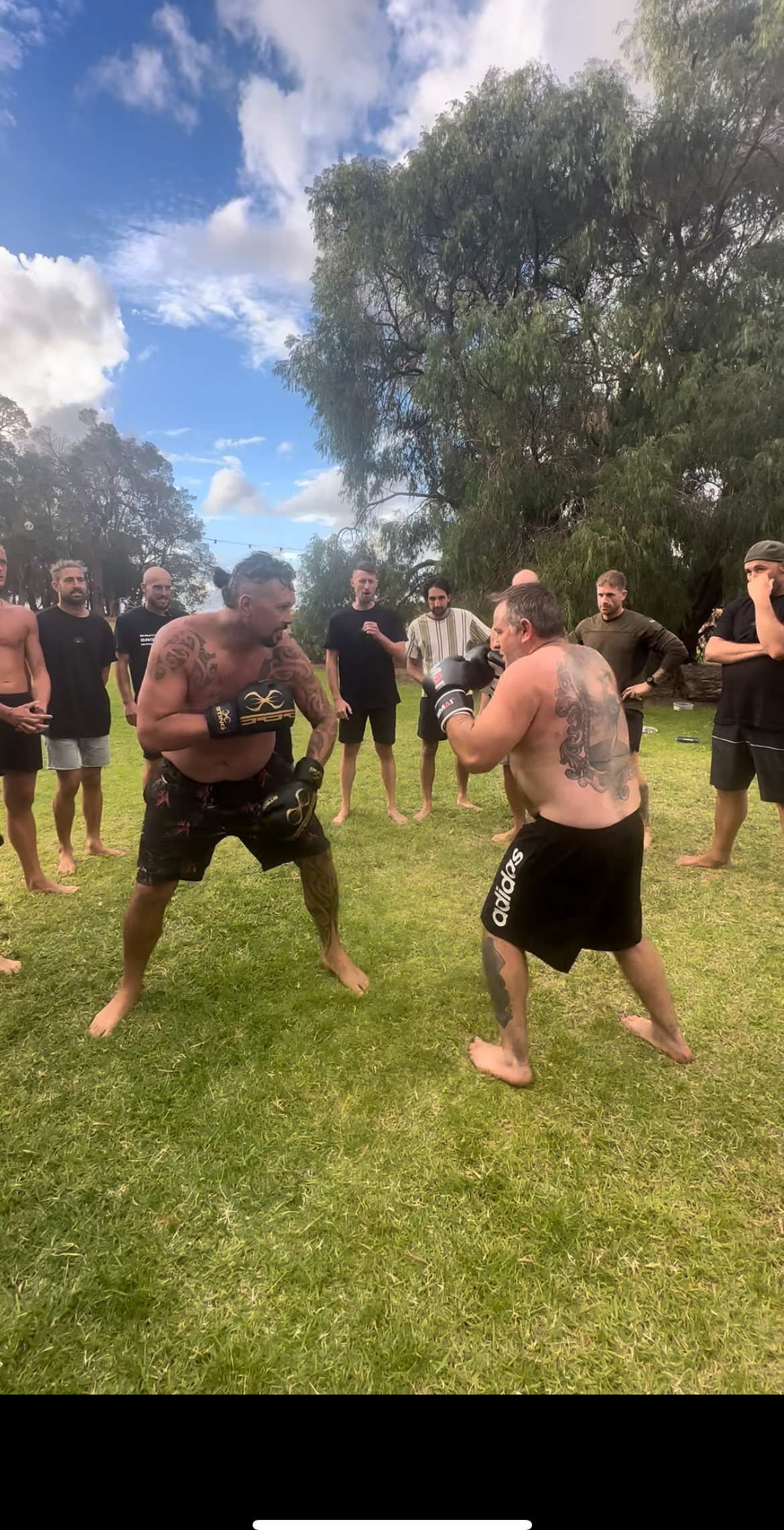 Two men sparring inside a circle of watching men