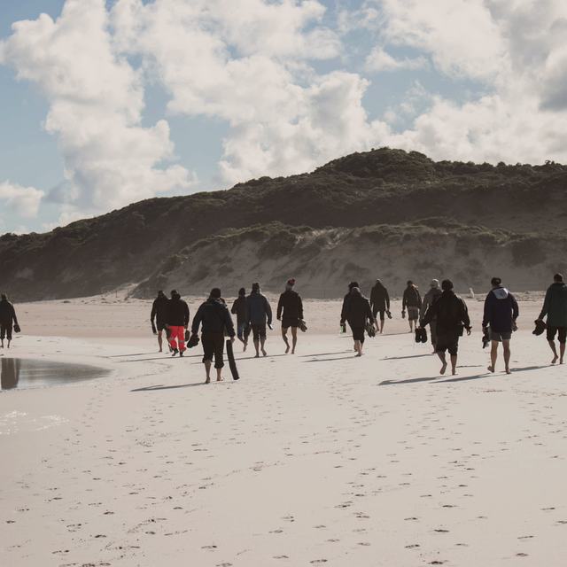 A line of men walking the shoreline